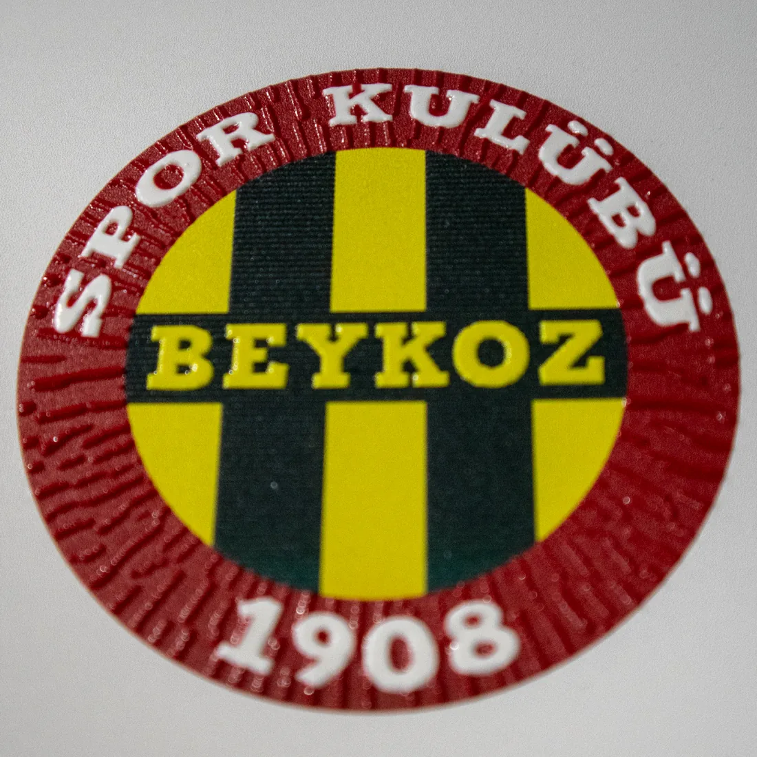 UV printed badge — Printed badge cured under UV light, with a raised outline.