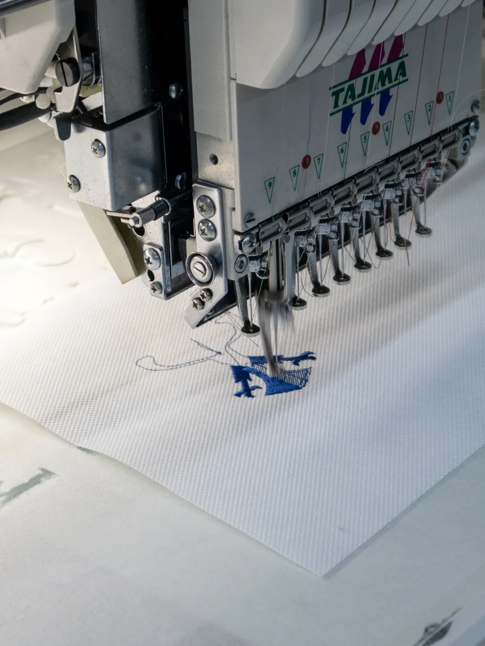 Embroidery head stitching a crest, close up