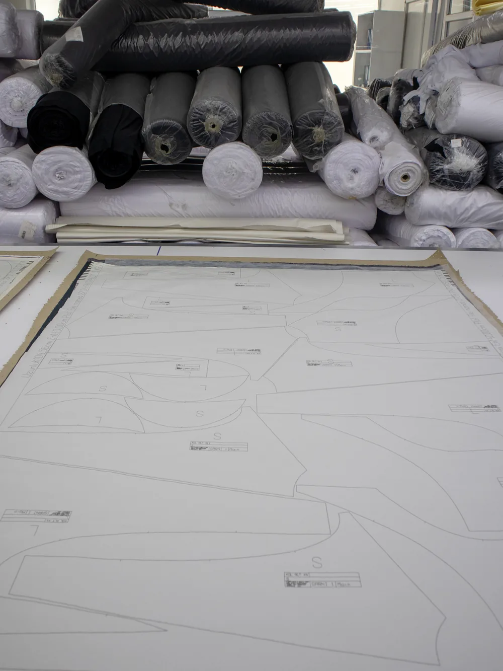 Graded pattern marker laid out beside stacked fabric rolls
